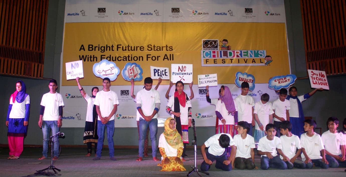Young people on stage at a children's festival holding placards reading No Child Marriage, Equality and Child Rights