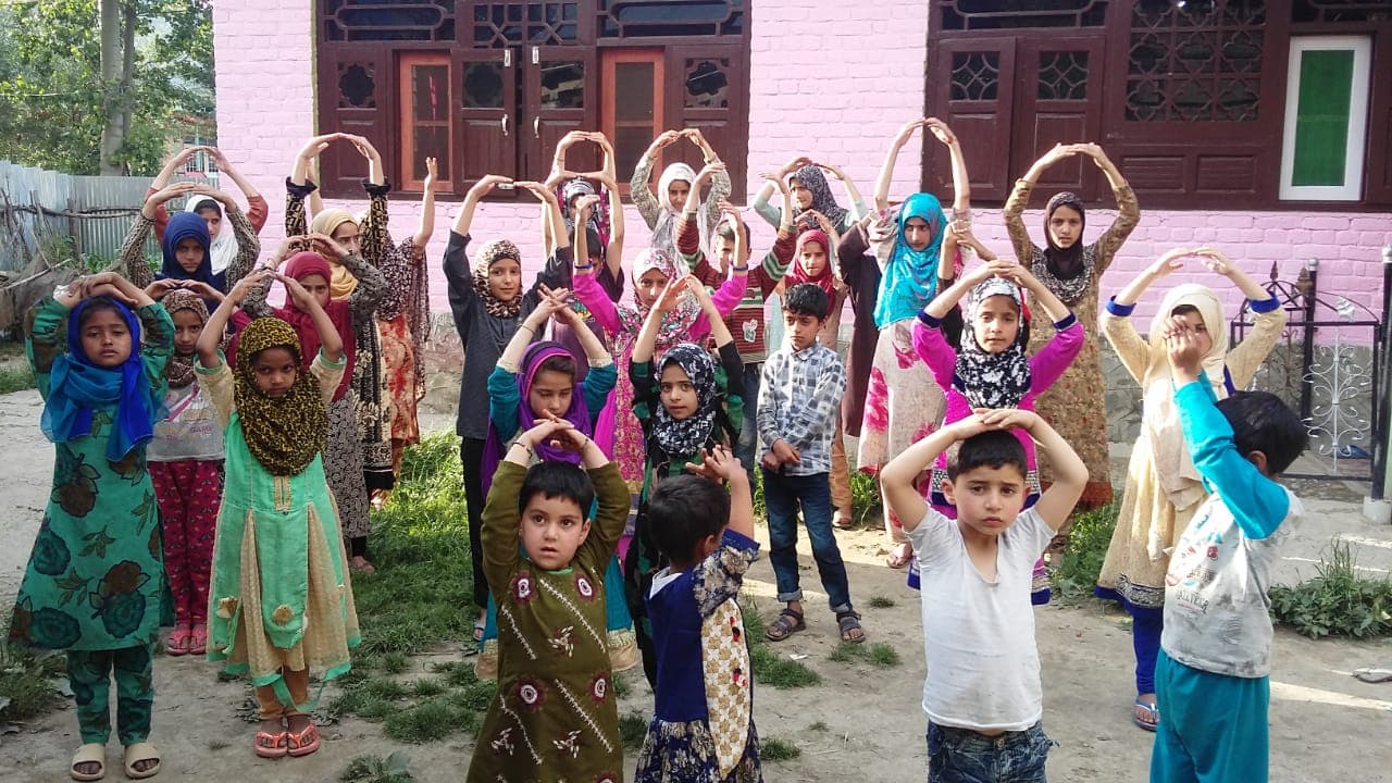 Children standing in rows outside a community learning centre during a group activity