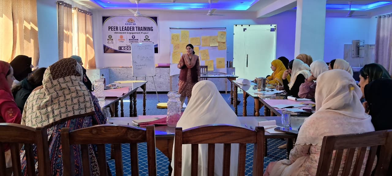A trainer leading a room of women participants at a KOSHISH peer leader training workshop